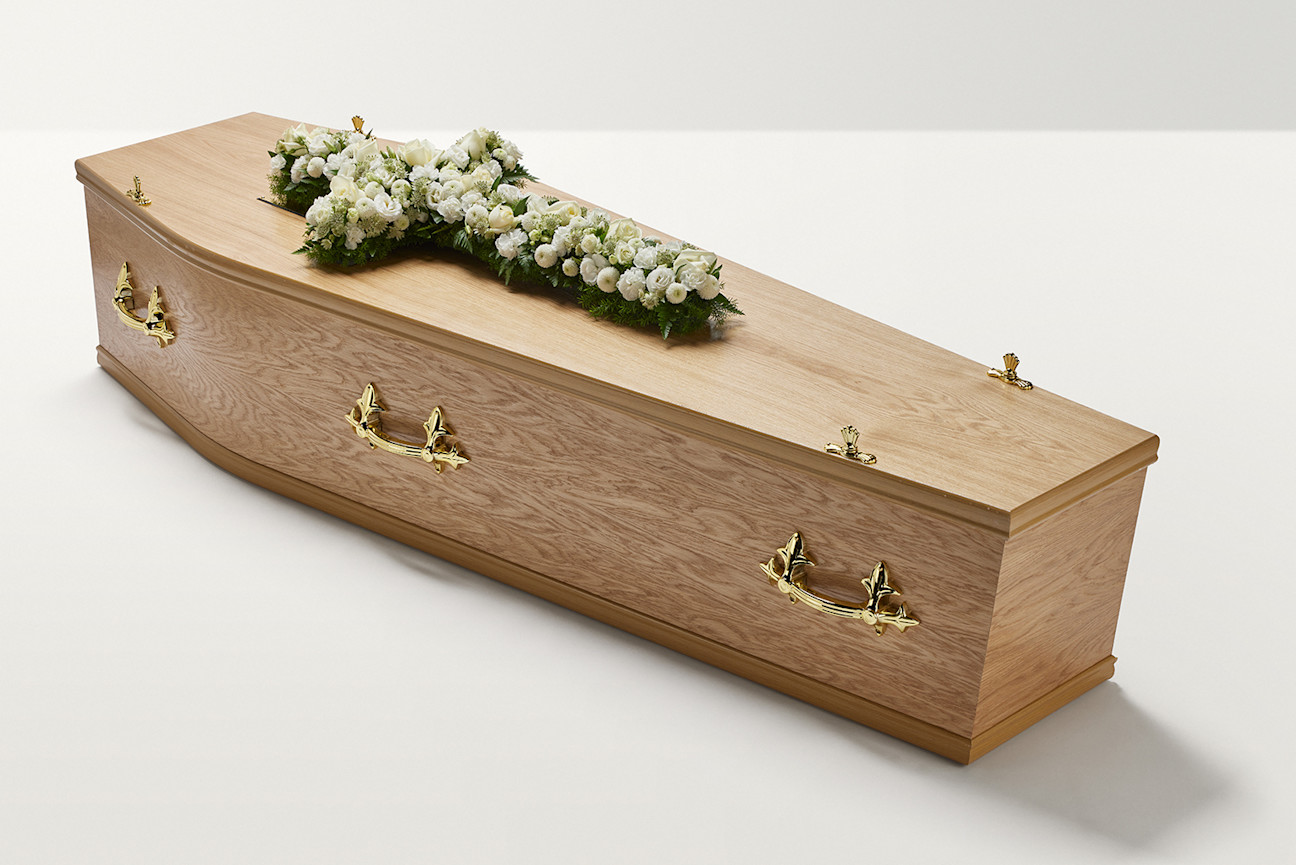 Zoomed out shot of white flowers in the shape of a cross on coffin