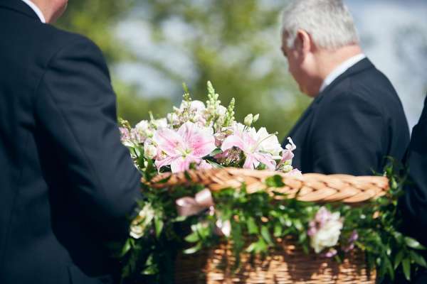 Coffin topped with flowers being carried