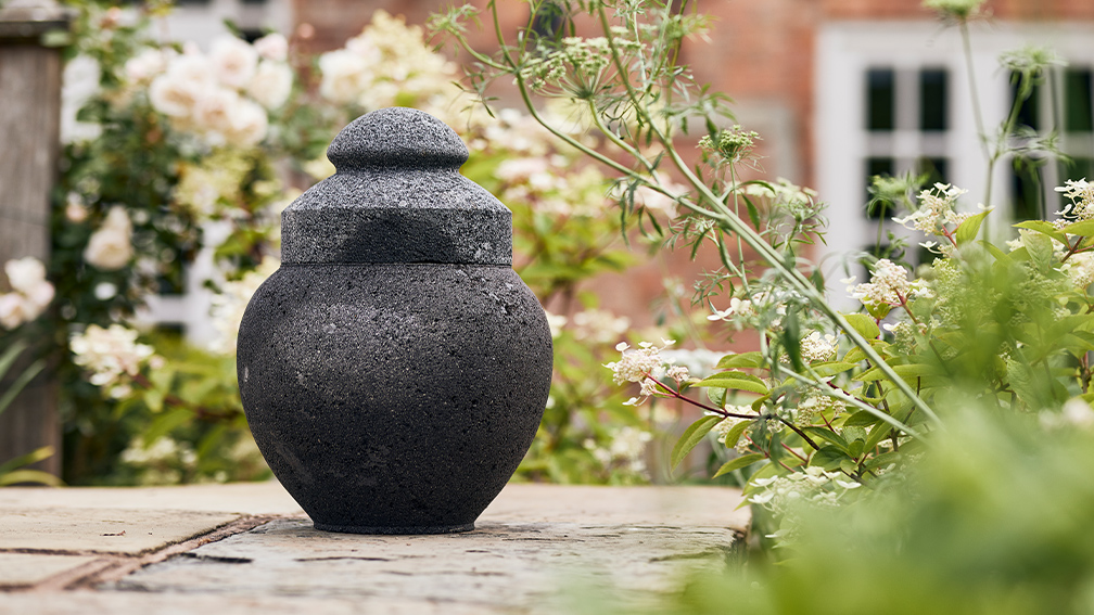 Black urn outside in a garden.