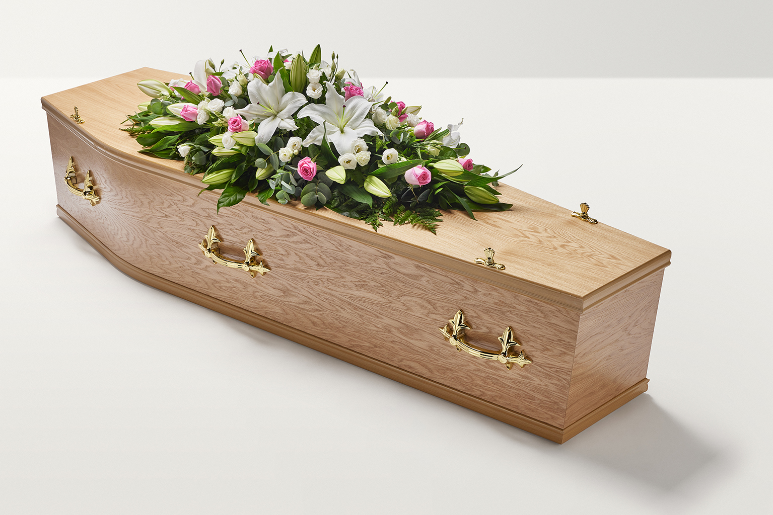 Zoomed out shot pink and white rose and lily floral display on top of coffin