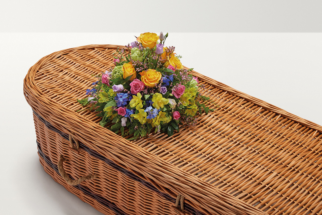 Brightly coloured rounded flower display on top of coffin