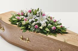 Pink and white rose and lily floral display on top of coffin