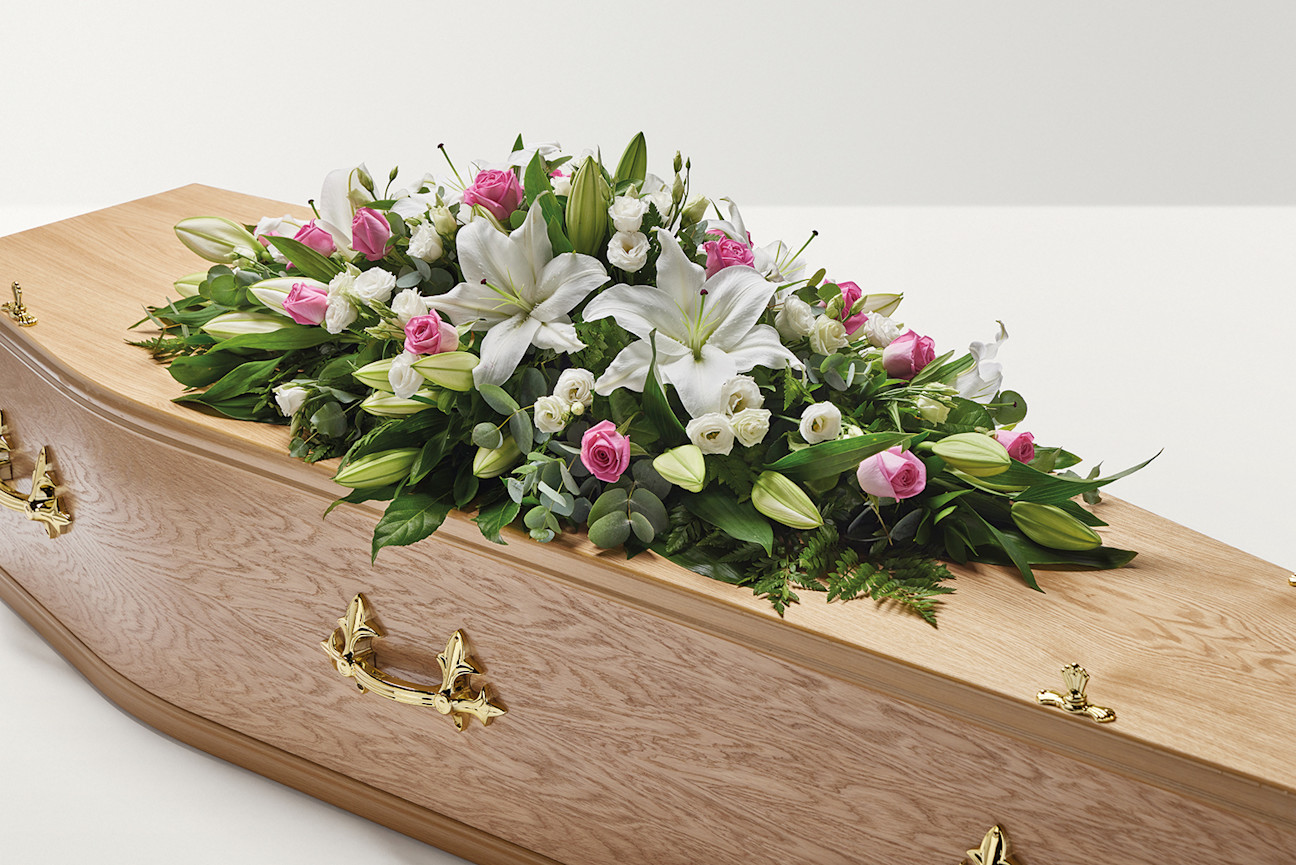 Pink and white rose and lily floral display on top of coffin