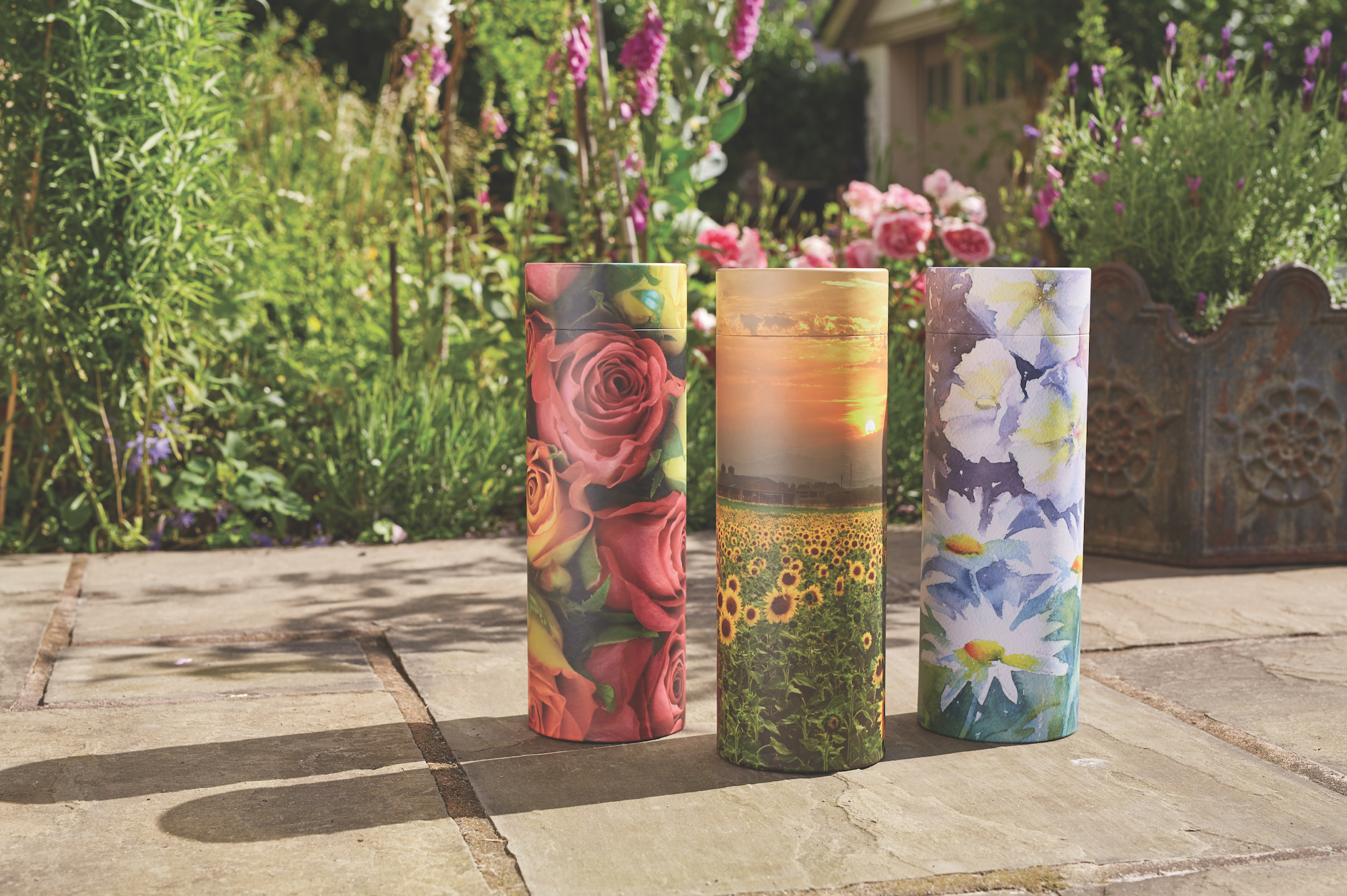 Three tubes with floral designs on a patio in a garden