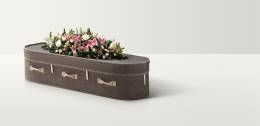 Full length image of grey wool coffin with a large bright flower spray