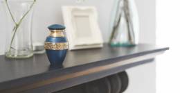Blue urn with gold band on black mantlepiece