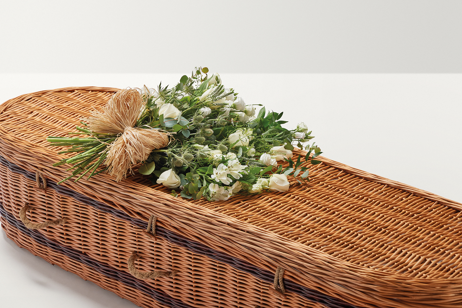 Large display of flowers with hand-tied bow on top of coffin