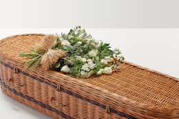 Large display of flowers with hand-tied bow on top of coffin