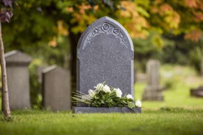 Grey natural headstone with white flowers laid.  