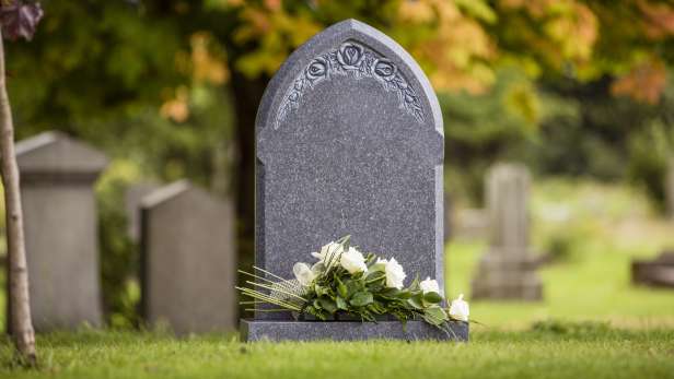 Grey natural headstone with white flowers laid.  