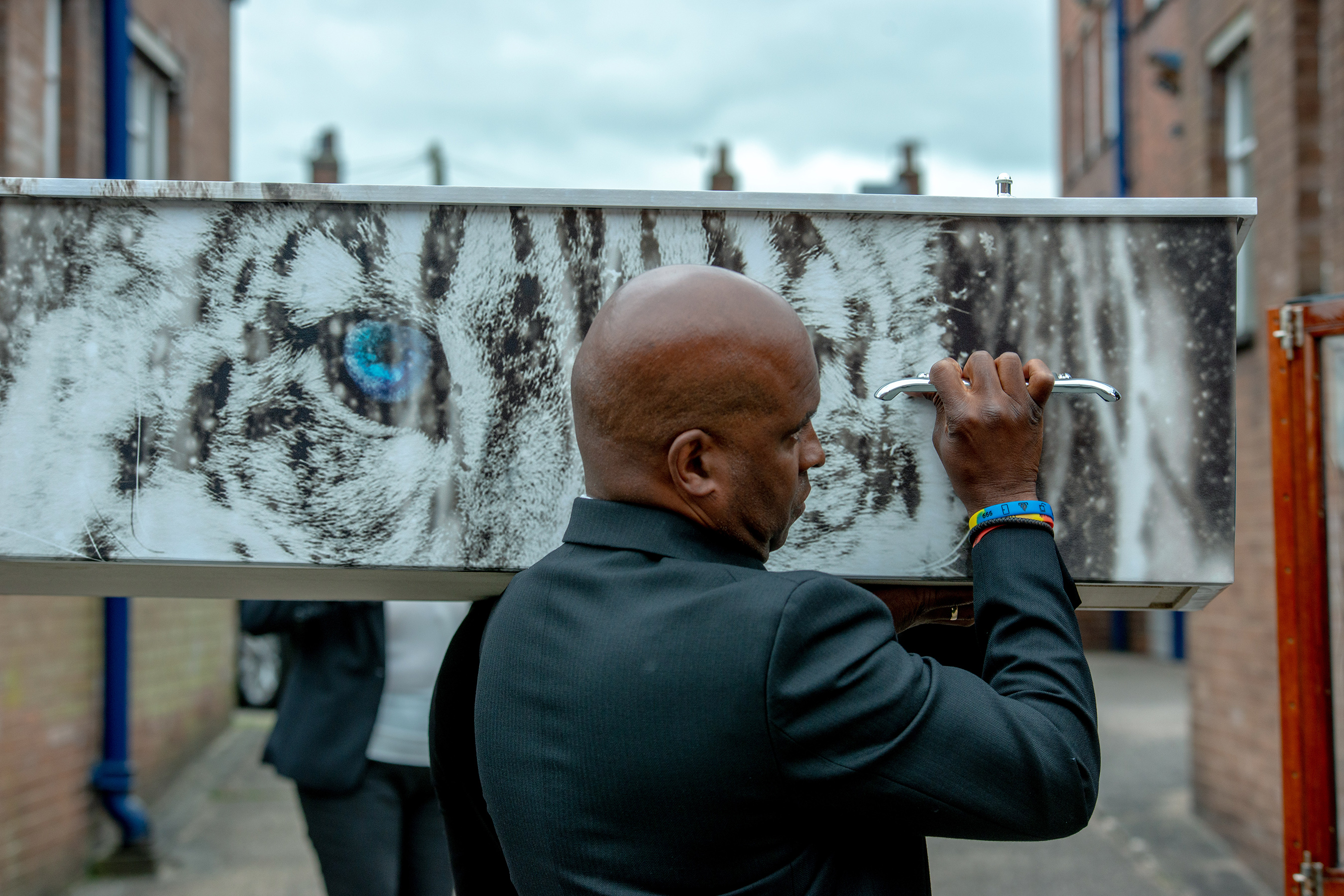 Man carrying a coffin with snow leopard print on