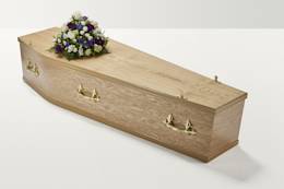 Zoomed out shot of white and purple flower display on top of coffin
