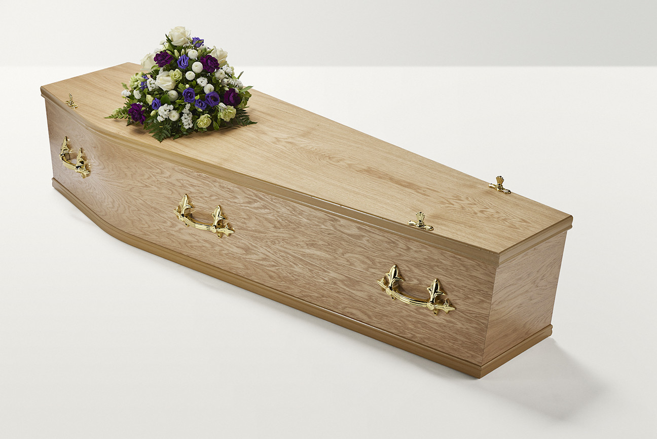 Zoomed out shot of white and purple flower display on top of coffin