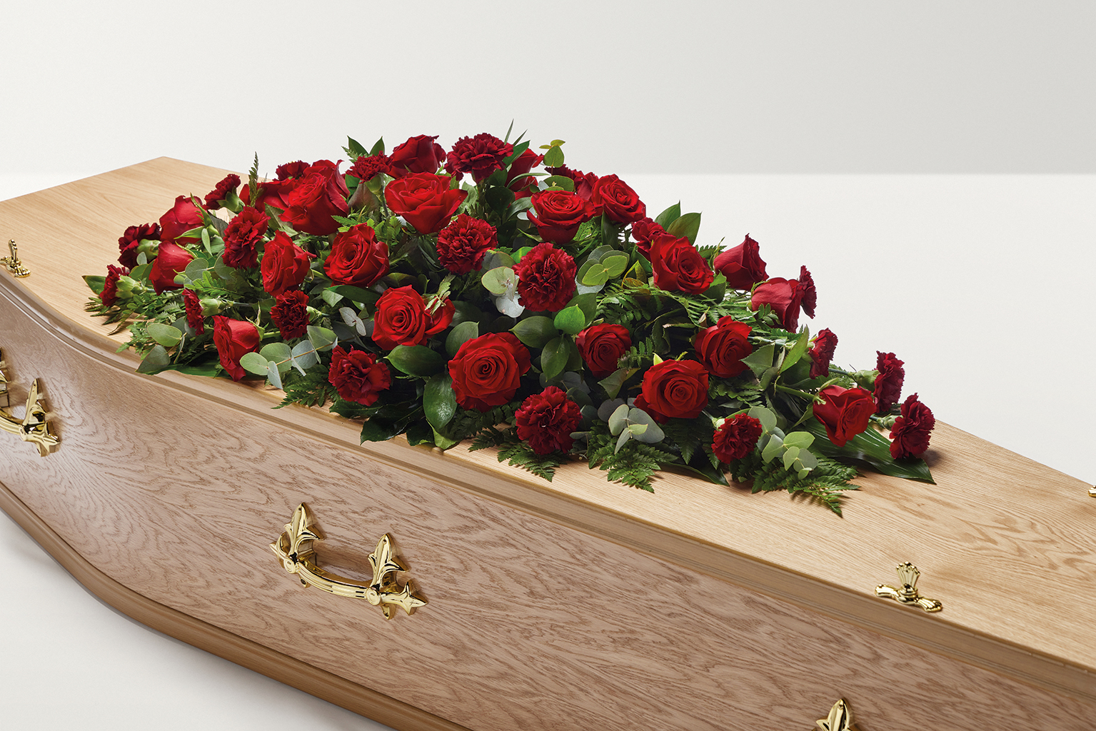 Red rose and carnation flowers on top of coffin