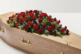 Red rose and carnation flowers on top of coffin