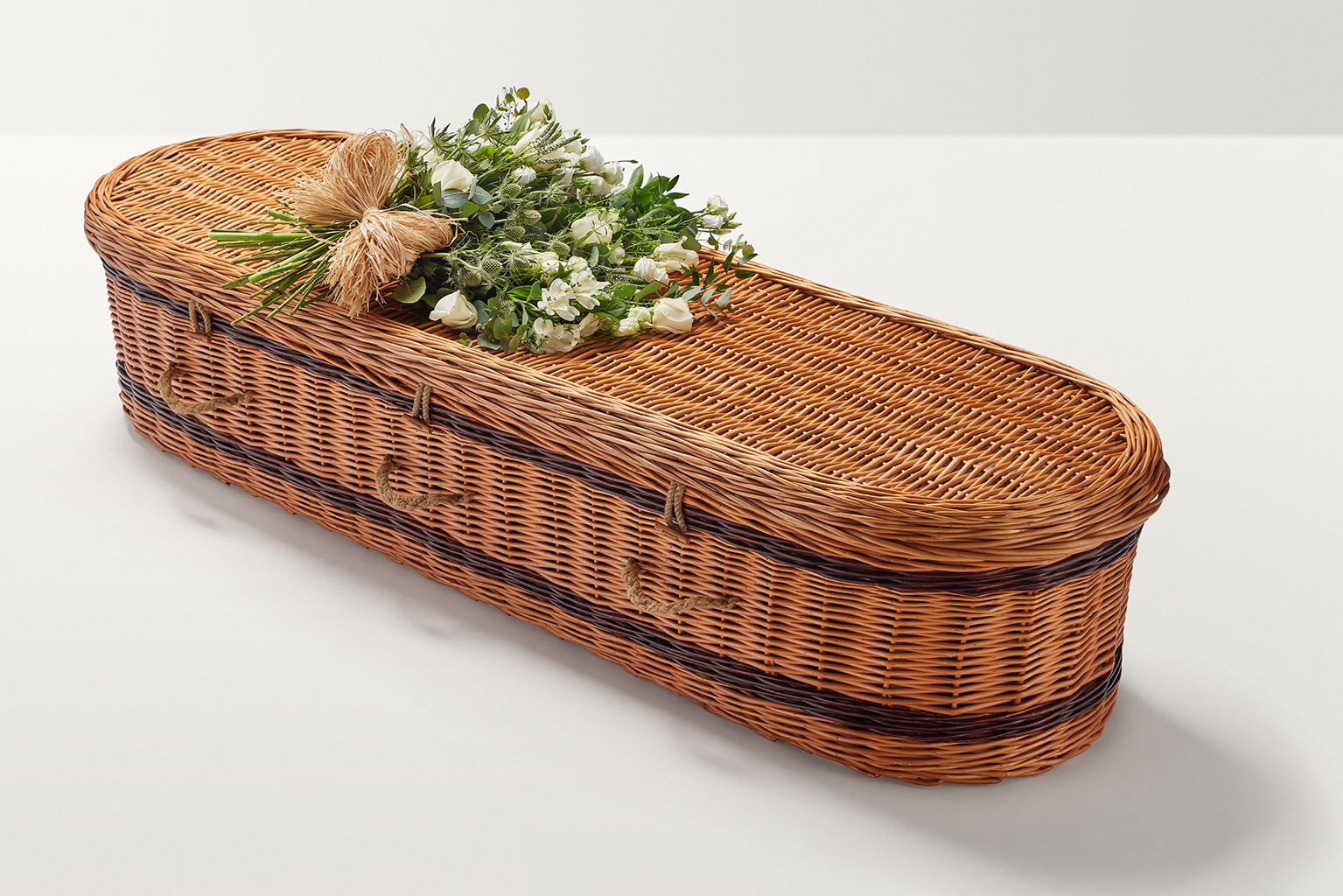 Zoomed out shot of large flowers with hand-tied bow on top of coffin