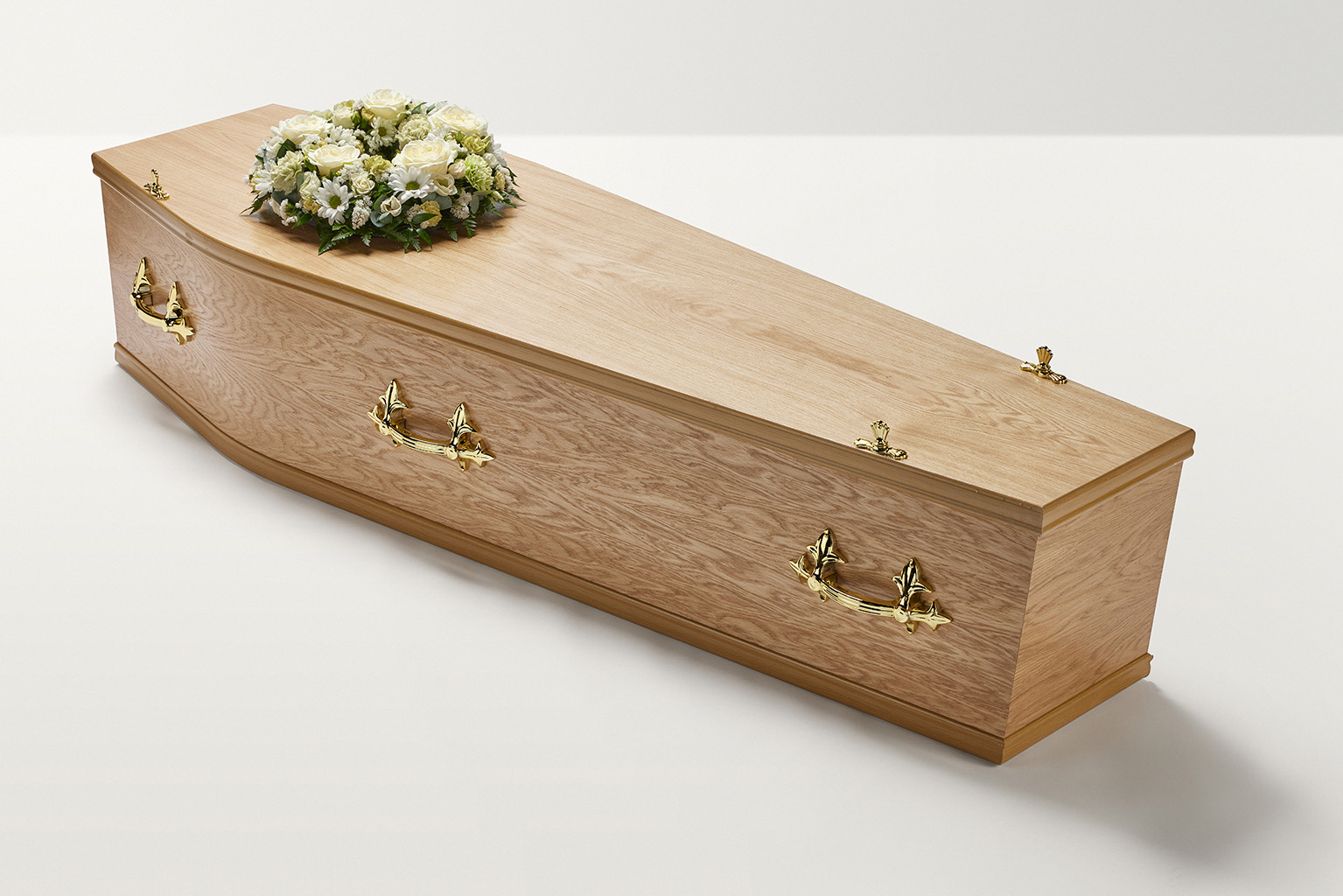 Zoomed out shot of white wreath of flowers on top of coffin 