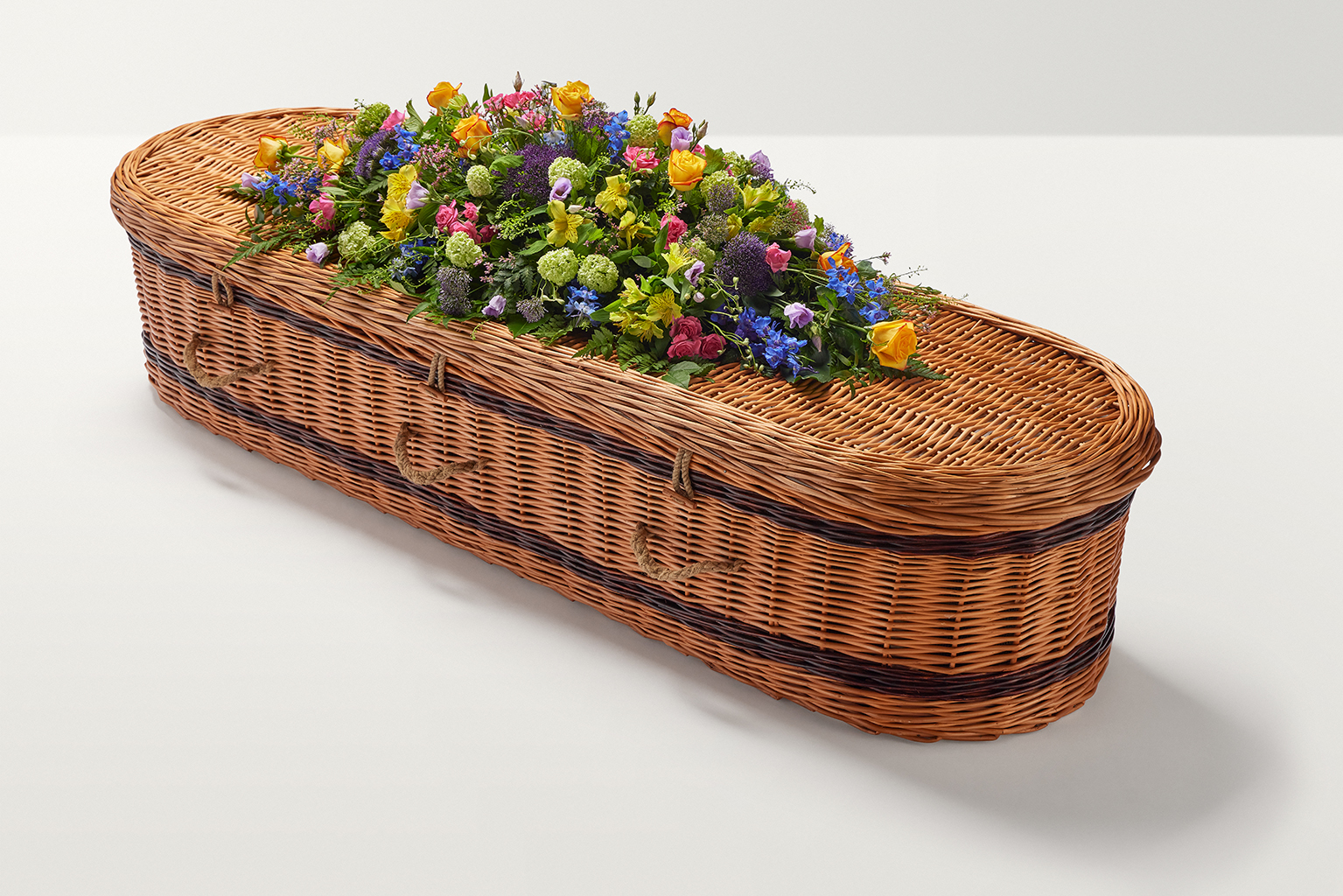 Zoomed out shot of brightly coloured flowers on top of coffin.