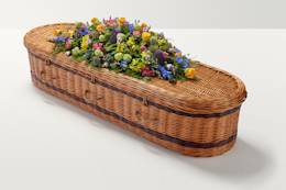 Zoomed out shot of brightly coloured flowers on top of coffin.