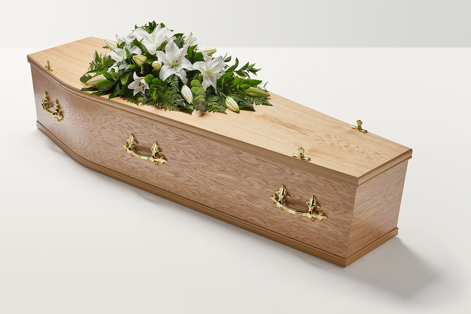Zoomed out shot of white lily flowers on top of coffin 