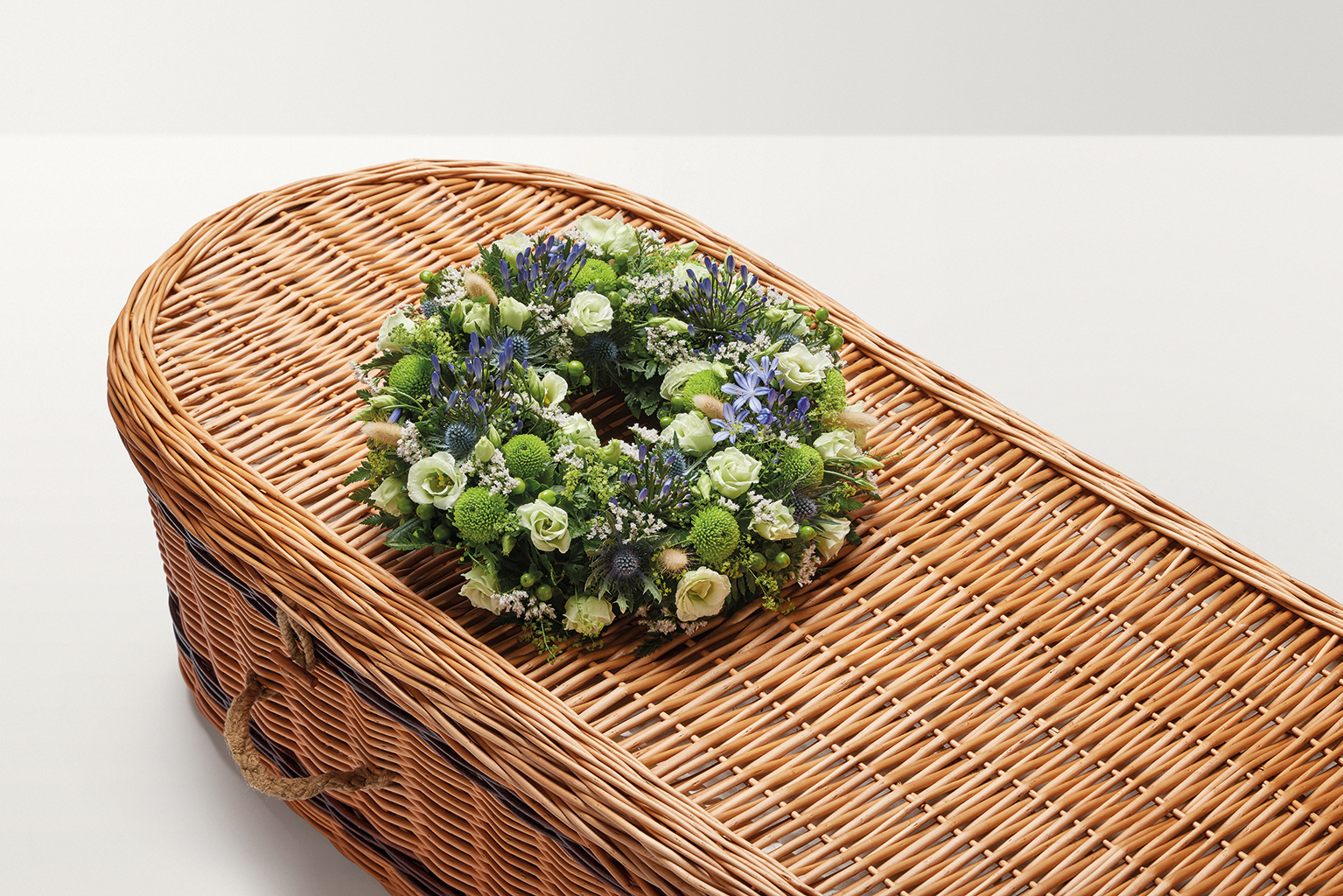 Blue and green wreath of flowers on top of coffin