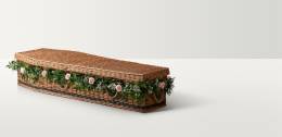 Full length image of the willow coffin in a natural colour with a floral garland