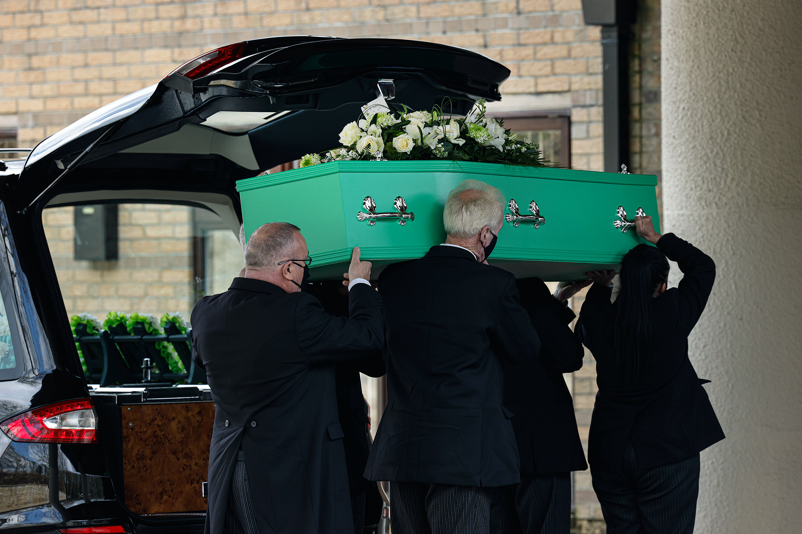 Green coffin being carried on a funeral 