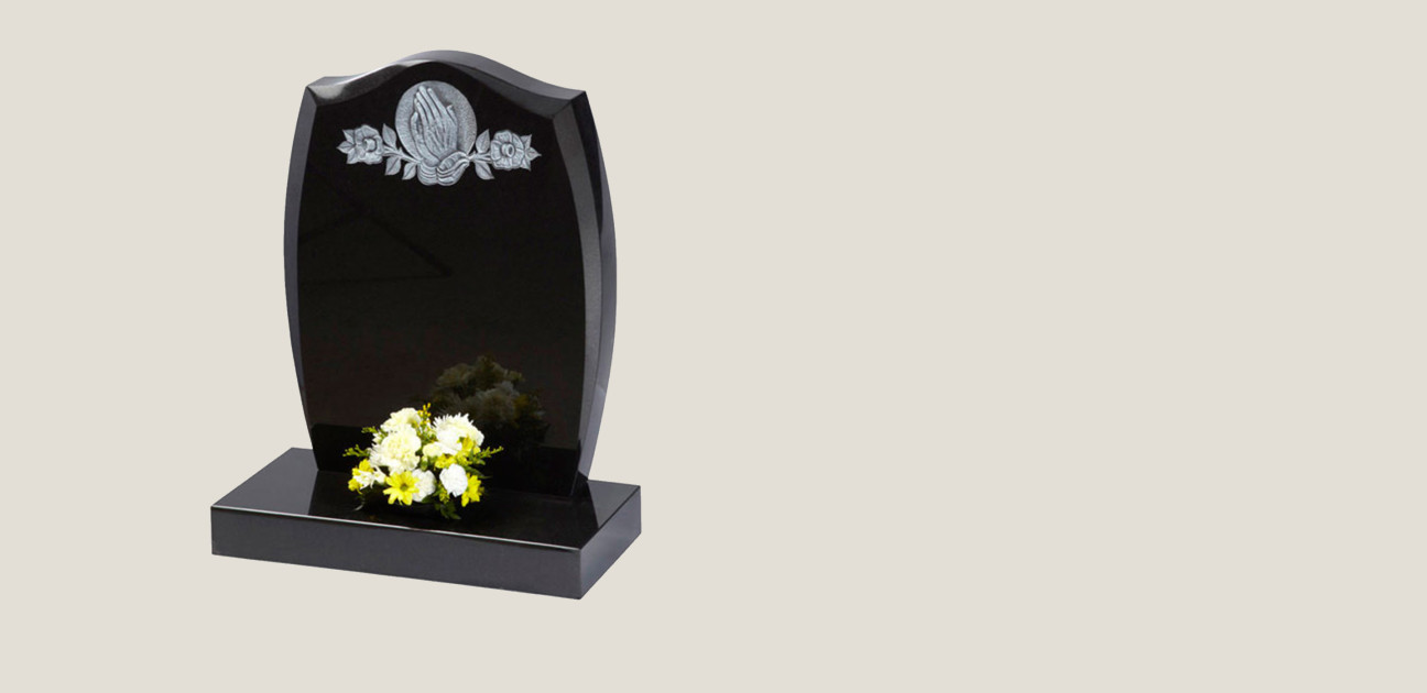 Curved black memorial with a silver inscription of praying hands and flowers