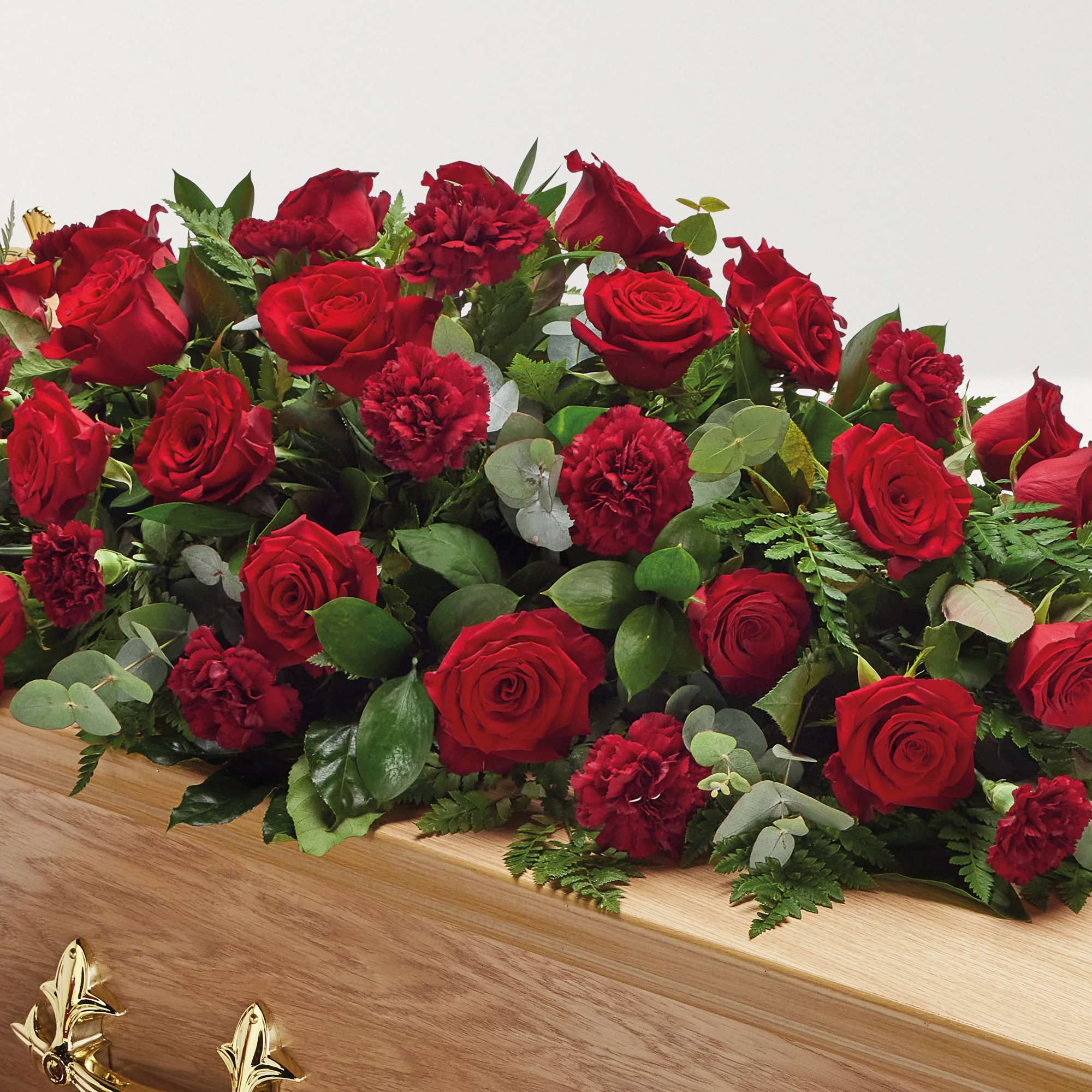 Zoomed in shot of red rose and carnation flowers on top of coffin