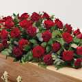Zoomed in shot of red rose and carnation flowers on top of coffin