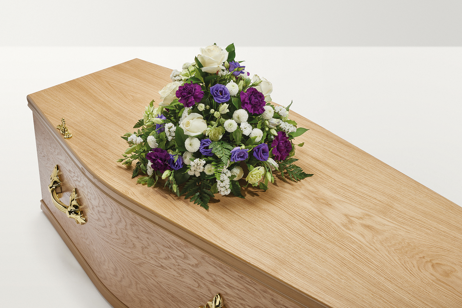 White and purple floral display on top of coffin