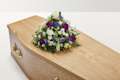 White and purple floral display on top of coffin
