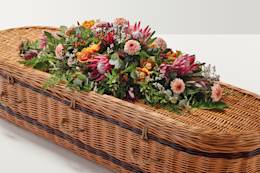 Peach coloured flower display on top of coffin