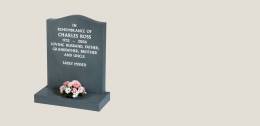 Black memorial with white inscription and pink floral arrangement