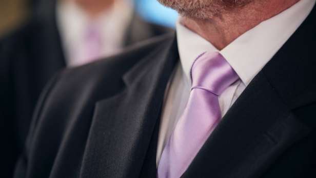 Man wearing a pink tie at a funeral