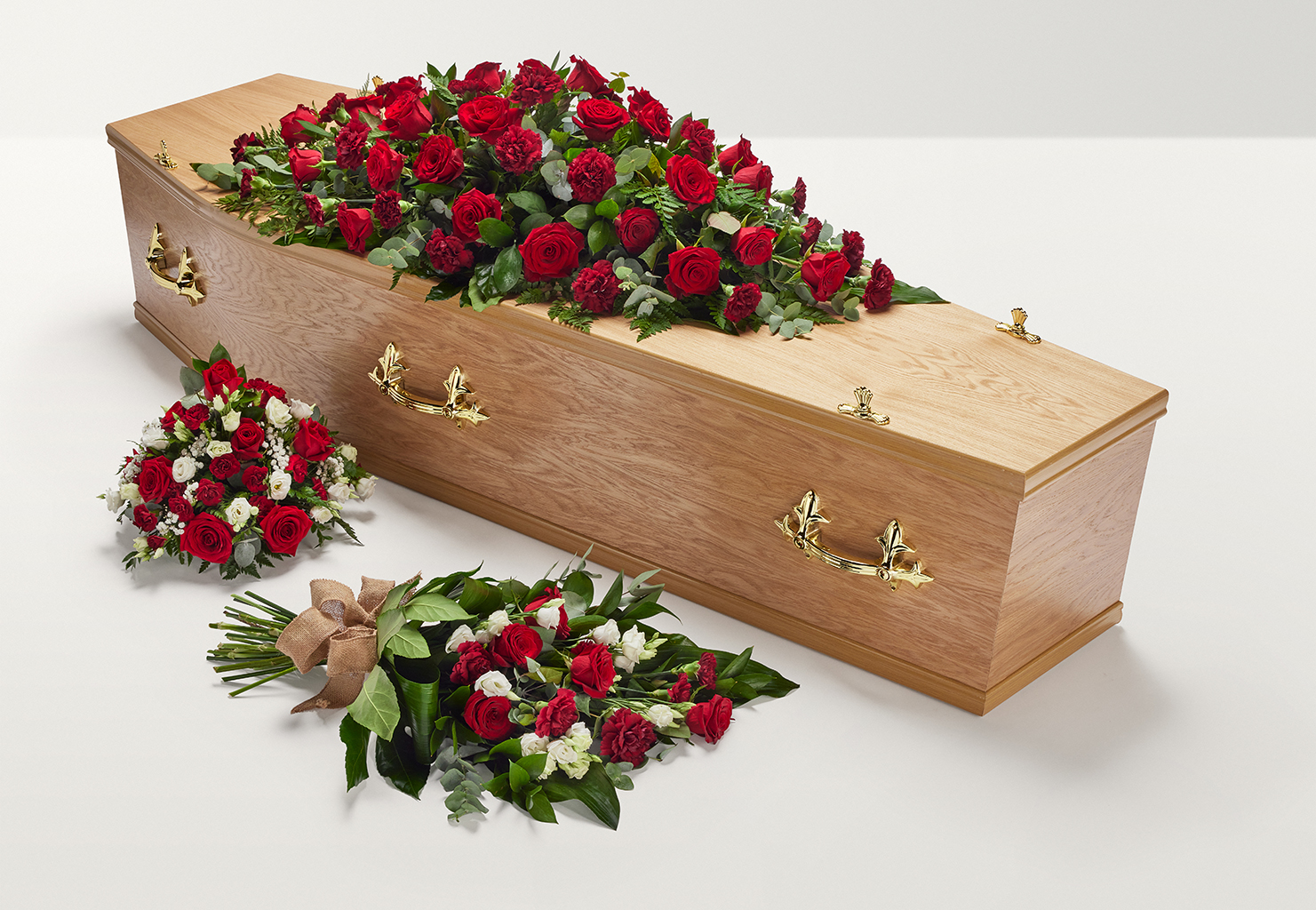 Zoomed out shot of red and white flowers on top and beside coffin