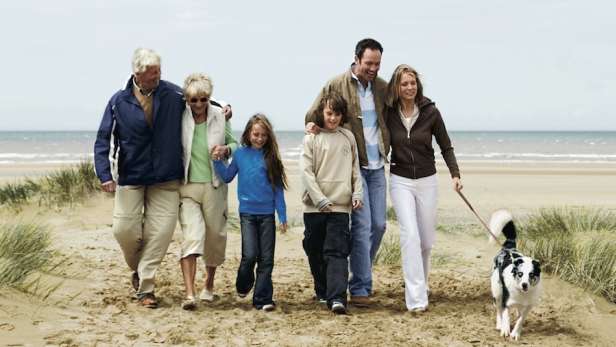 Family walking on a beach with a dog. 