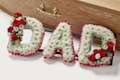 White and red flowers spelling out the word 'Dad' beside coffin