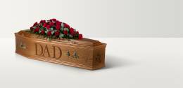 Full length image of a wooden coffin with 'Dad' engraved on the side and a rose spray