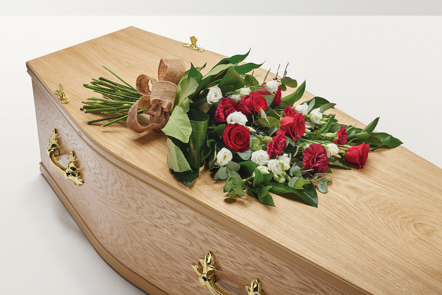 Red flowers with a hand-tied bow on top of coffin