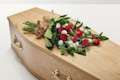 Red flowers with a hand-tied bow on top of coffin