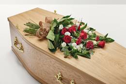 Red flowers with a hand-tied bow on top of coffin