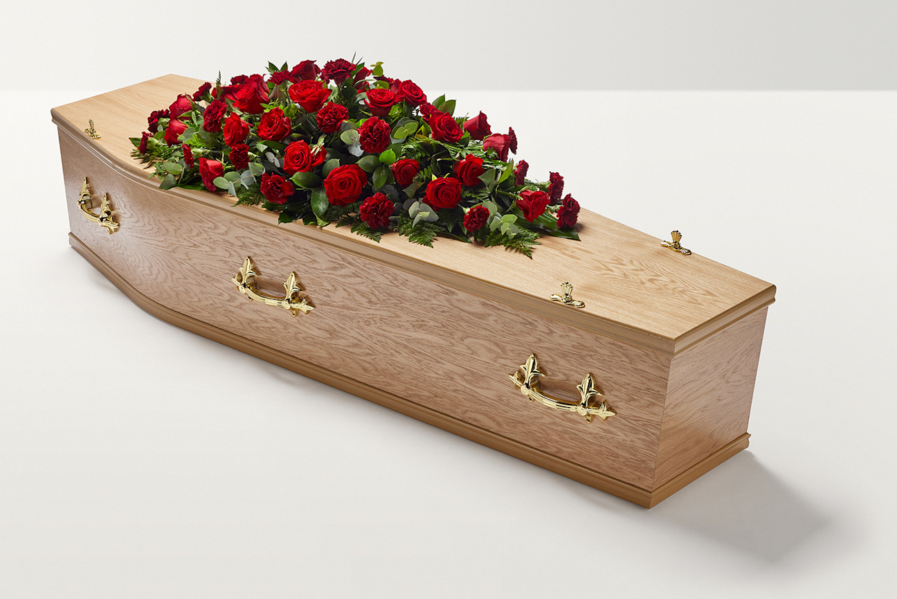 Zoomed out shot of red rose and carnation flowers on top of coffin