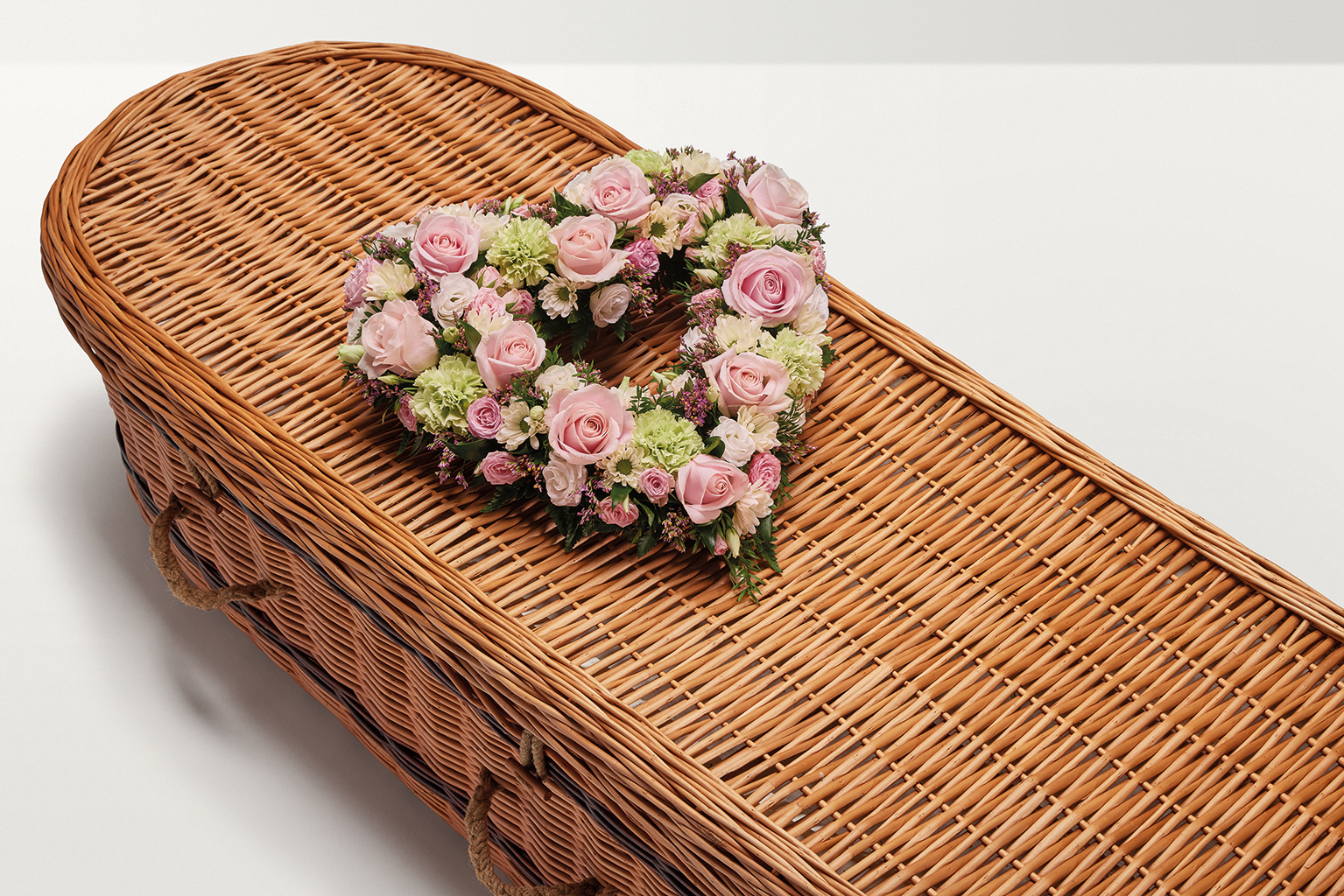 Pastel pink heart shaped flower display on coffin 