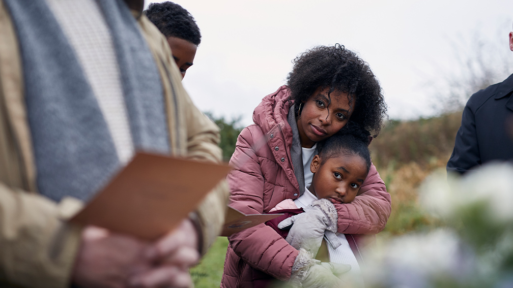 A woman comforting her daughter at a funeral.