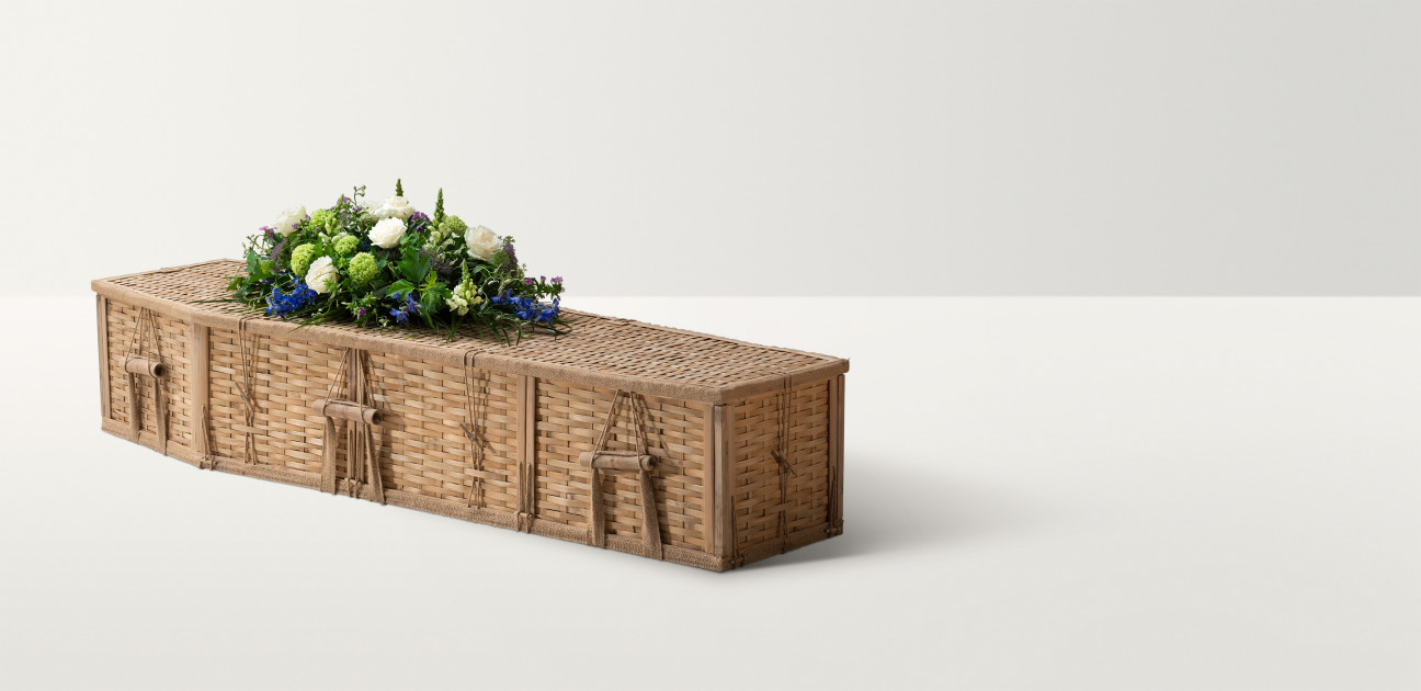 Bamboo coffin with white and blue floral arrangement on top