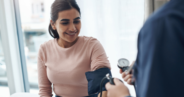 Doctor taking blood pressure from patient to help manage steroid side effects