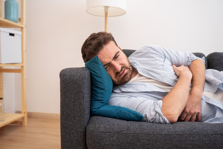 Man lying on the sofa feeling pain and stomach ache