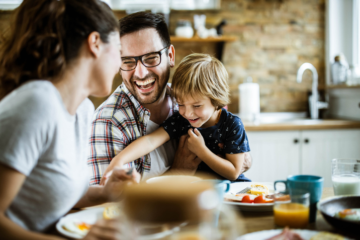 Young cheerful family having fun at dining table