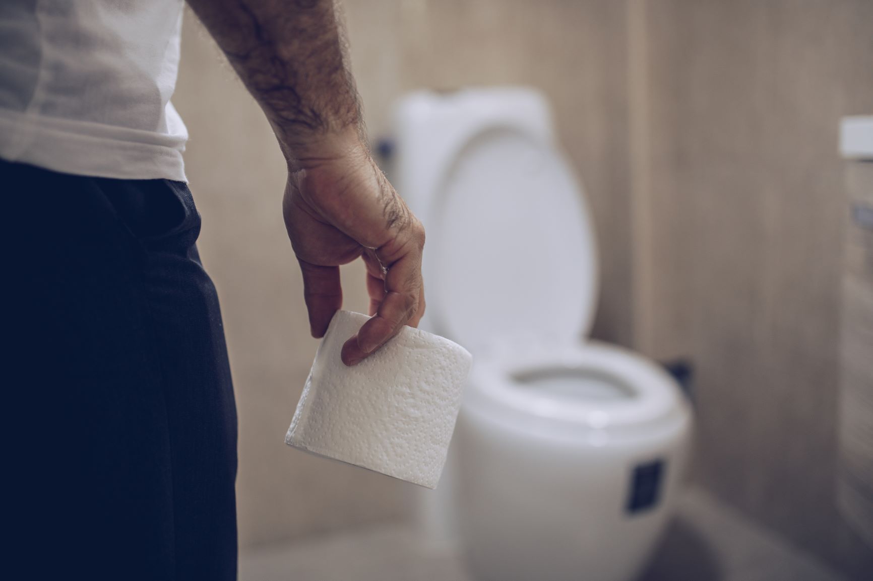 Homme portant un rouleau de papier toilette marchant vers les toilettes